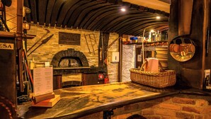 A rustic interior with a brick wall, a stone oven, and a wooden counter. - Hotel Center (Bohinj)