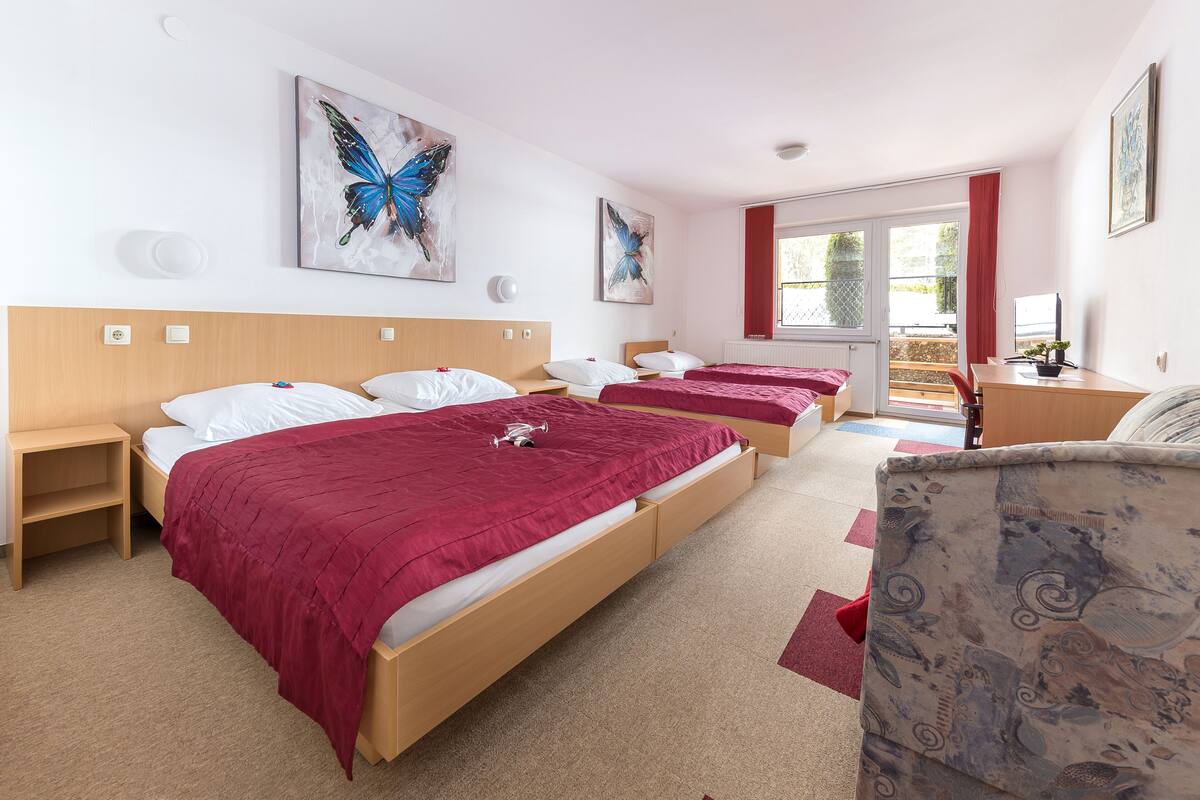 A hotel room with two beds, a desk, a chair, and artwork on the walls.