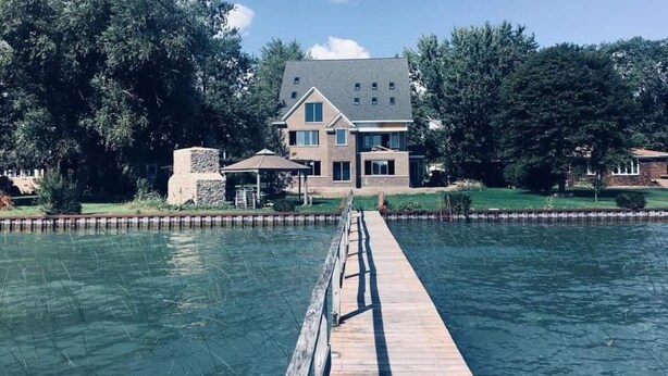 Una casa con piscina y terraza de madera que la conecta.
