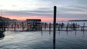 Un muelle se adentra en aguas tranquilas con un atardecer de fondo.