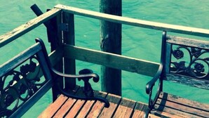 Un muelle de madera que se adentra en aguas turquesas, con barandilla de metal.