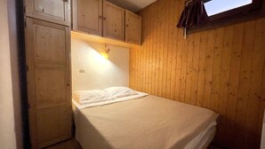 A small, cozy room with a single bed, wooden walls, and a window. - RESIDENCE 2-234 - Village center apartment, close to the slopes - Wi-Fi - Garage (La Clusaz)