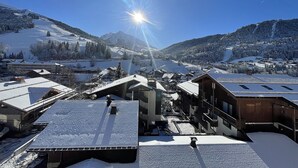 A snow-covered village with buildings and a mountain backdrop. - RESIDENCE 2-234 - Village center apartment, close to the slopes - Wi-Fi - Garage (La Clusaz)