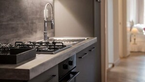 Een moderne keuken met een gasfornuis, een roestvrijstalen kraan en een verlichte achterwand.