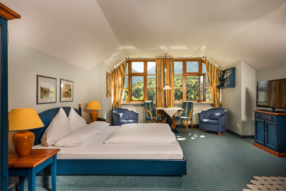 Een hotelkamer met een groot bed, twee stoelen, een tafel en een televisie.