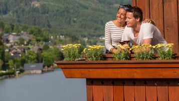 A wooden deck with a railing, overlooking a lake and a village.