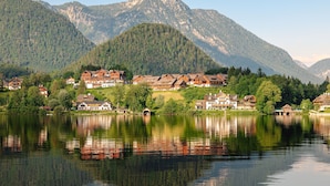 A lakeside village with traditional wooden houses, a clear view of the lake, and mountains in the background.