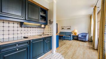 Una cocina compacta con armarios azul oscuro, salpicadero de azulejos y piso de madera.