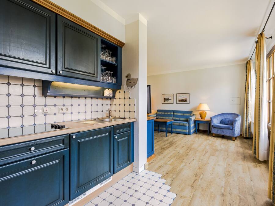 Una cocina compacta con armarios azul oscuro, salpicadero de azulejos y piso de madera.