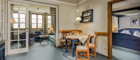 A hotel room with a dining area, a sofa, a table with chairs, and a bed.