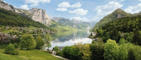 A serene lakeside village with traditional houses, a clear sky, and lush greenery.