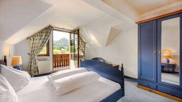 Ein Schlafzimmer mit einem großen Bett, einem Kleiderschrank, einem Fenster mit Vorhängen und Blick ins Freie.