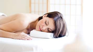 A person lying on a bed with a white pillow and a white blanket.