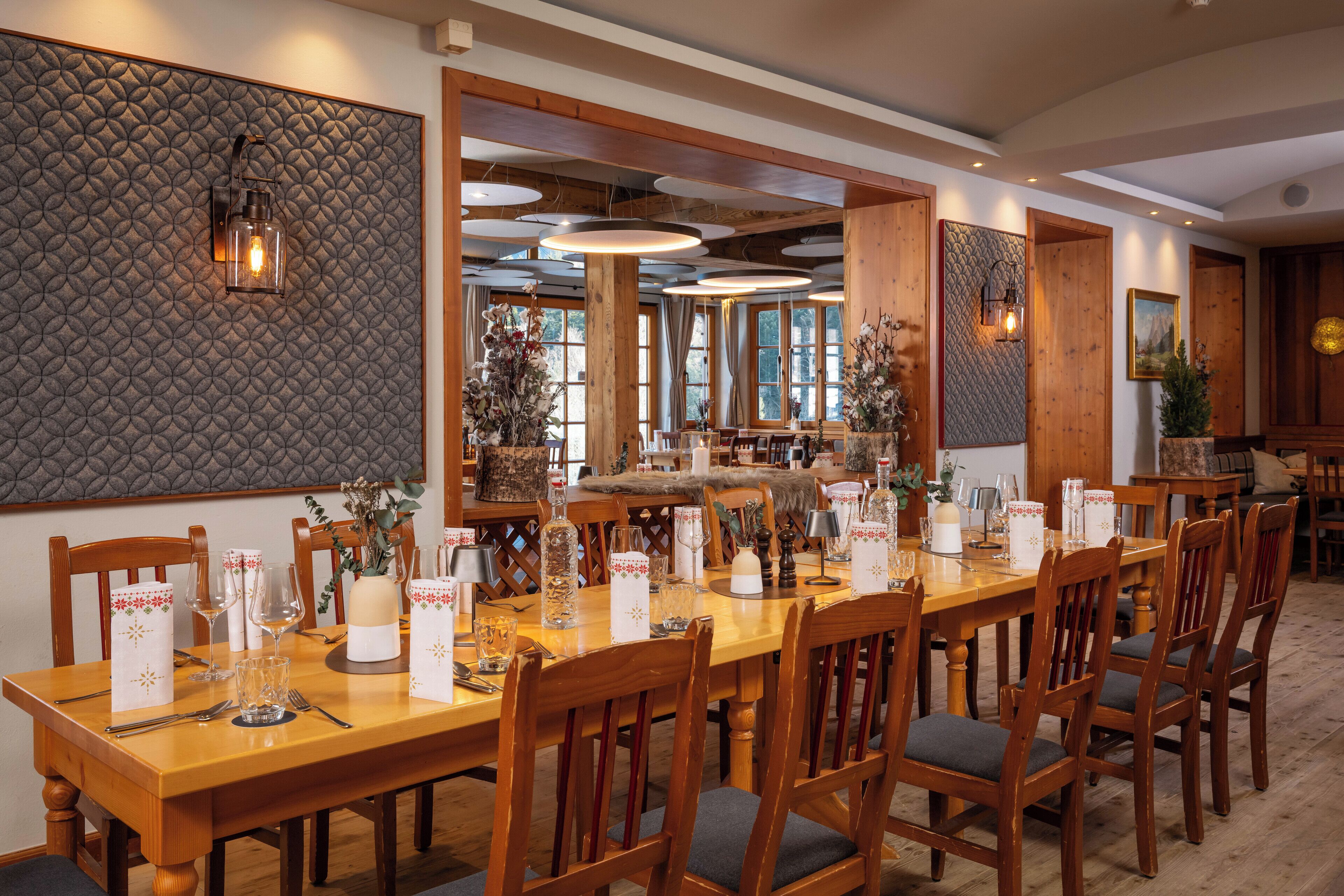 A dining area with a long wooden table set for a meal, surrounded by wooden chairs with cushioned seats.