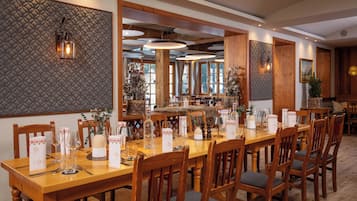 Un comedor con una larga mesa de madera dispuesta para una comida, rodeada de sillas de madera con asientos acolchados.