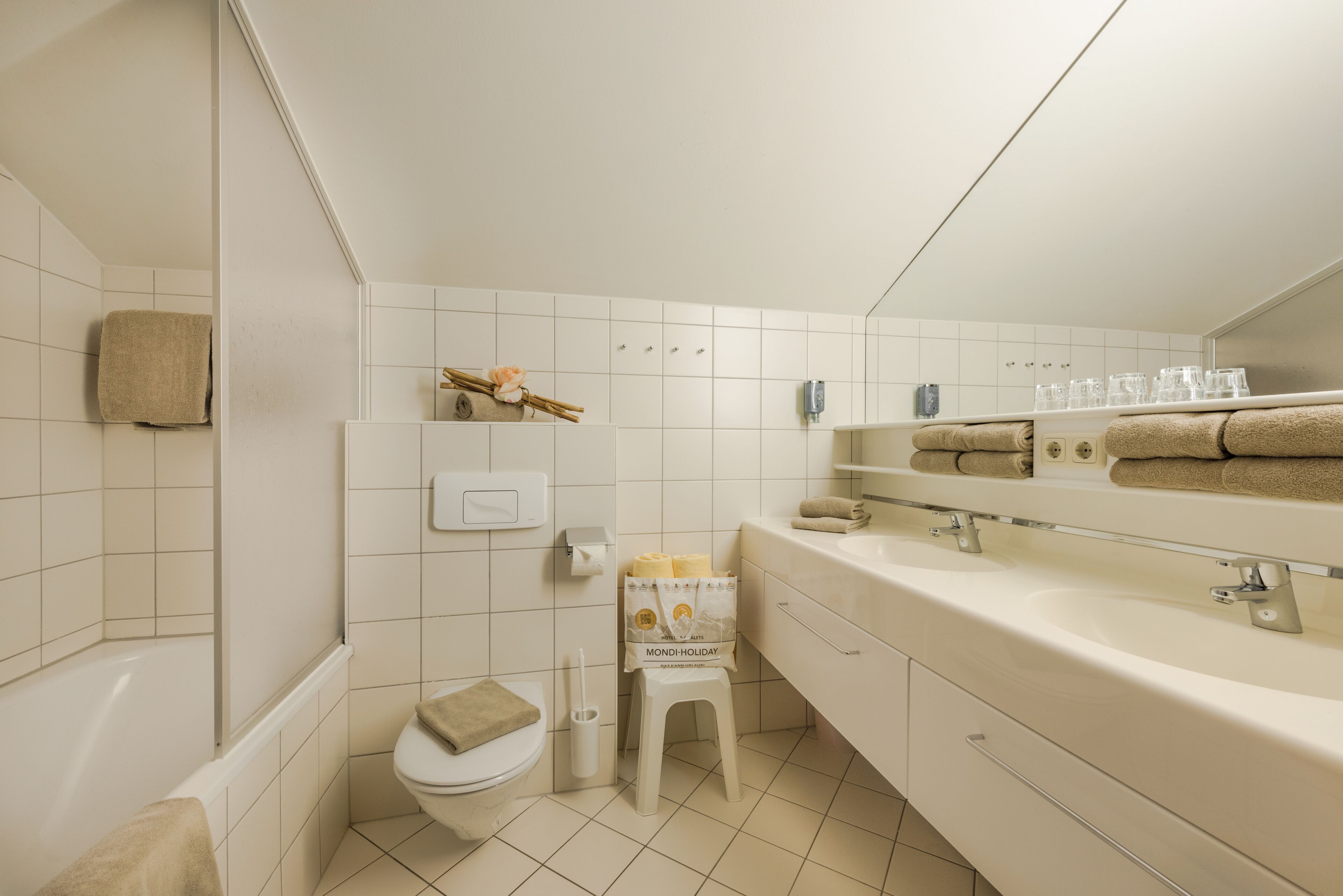 A modern bathroom with a bathtub, toilet, and vanity with a mirror.