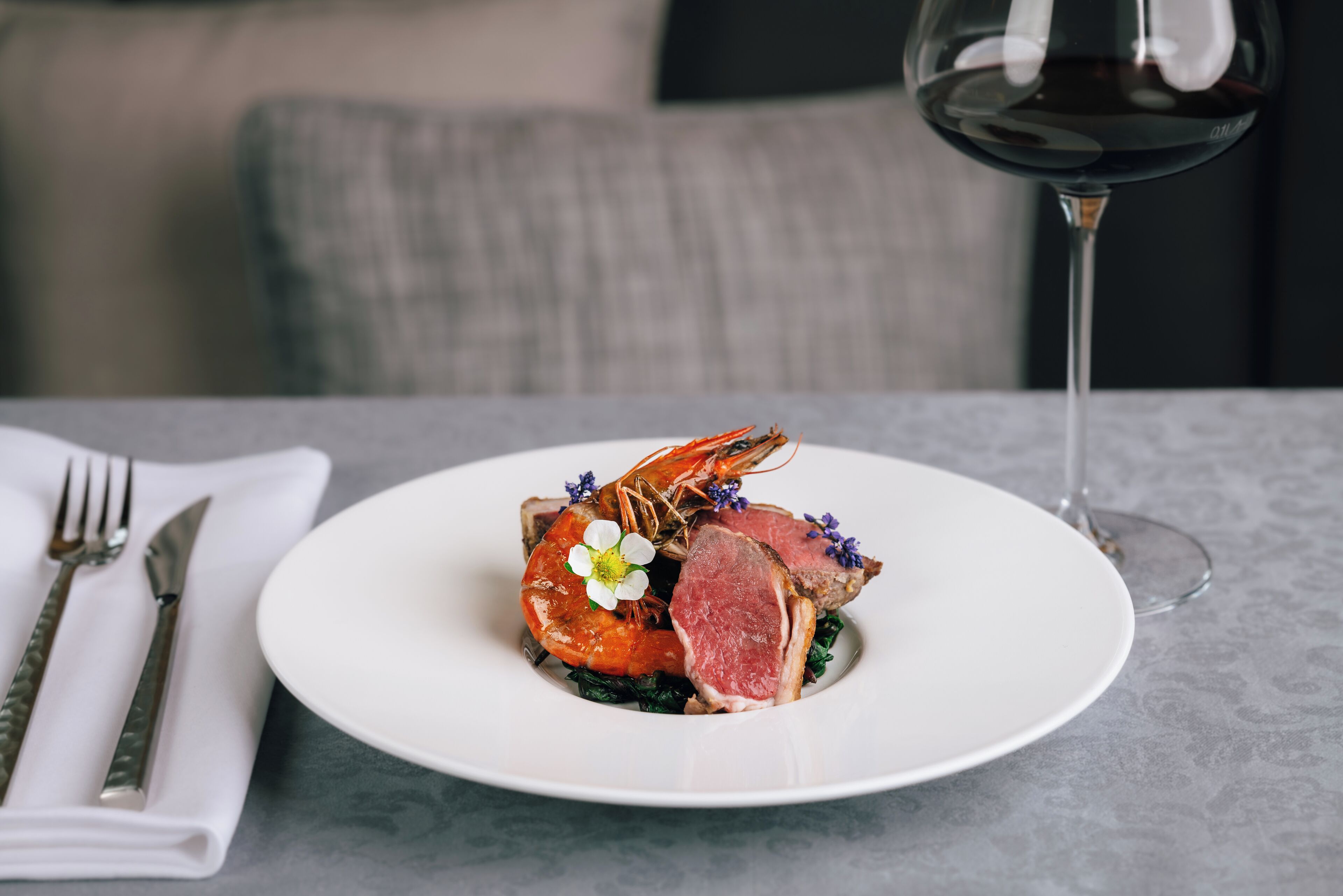 A plate of food with a glass of red wine on a table.