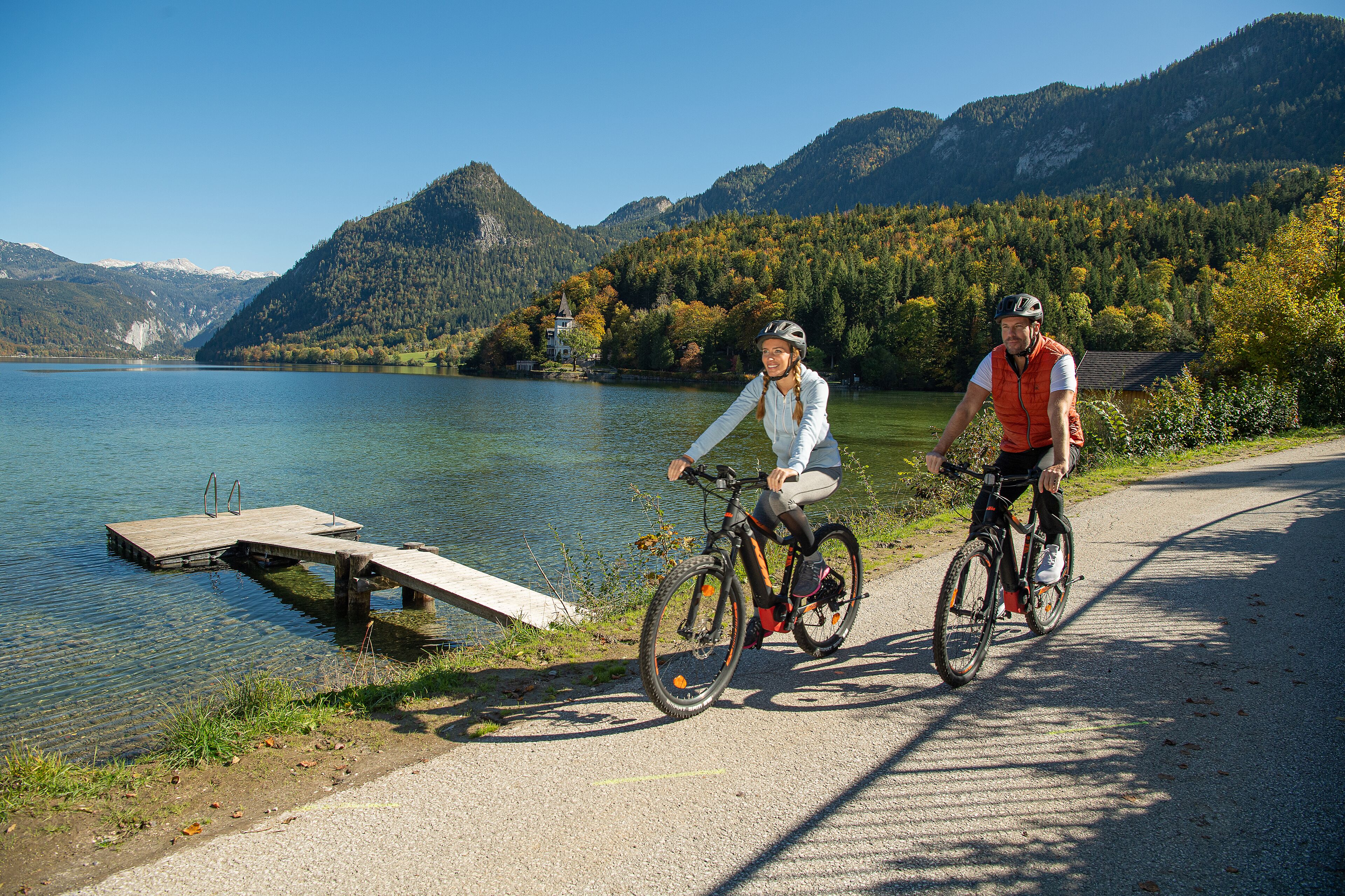 A lake with a wooden dock, surrounded by mountains and trees.