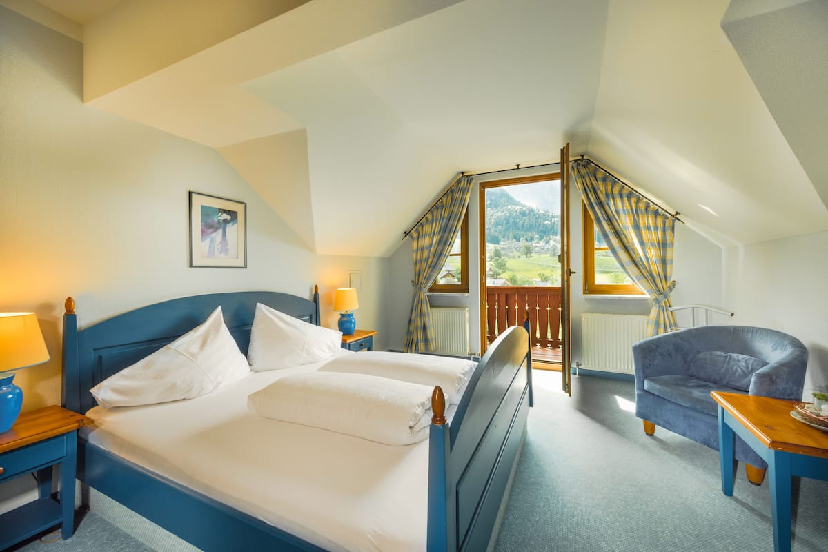 Een slaapkamer met een groot bed, een stoel, een tafel en uitzicht op de omgeving.