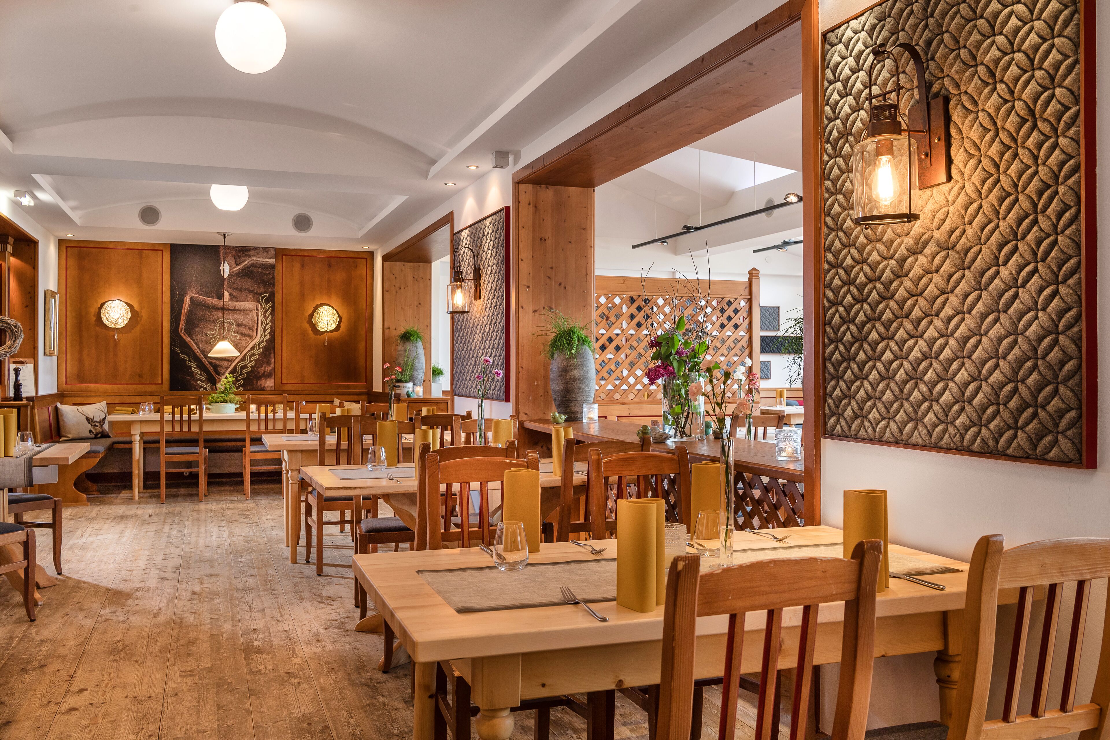 Een restaurant met houten tafels en stoelen, een behang met patroon en hanglampen.