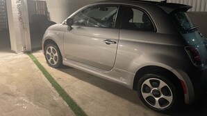 A silver compact car parked in a garage with a concrete floor and a green line marking.