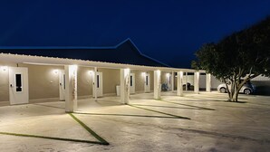 A hotel with a covered outdoor area, numbered rooms, and a car parked nearby.