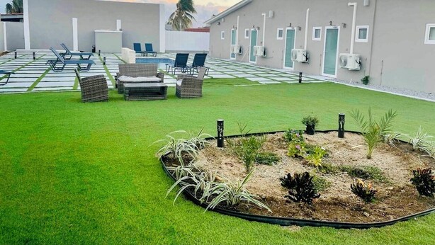 A hotel courtyard with a pool, outdoor seating, and a well-maintained garden.