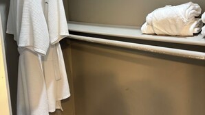 Een badkamer met een handdoekhouder met twee witte handdoeken en een plank met een opgevouwen handdoek.