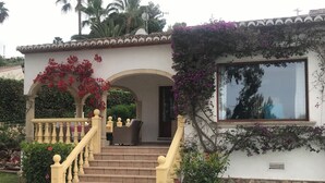 A house with a staircase leading to a porch, a window, and a garden with red flowers. - Beautiful Family Villa in Javea, Private pool, Free Wifi, Parking (Xàbia)
