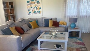 A living room with a grey sofa, colorful cushions, a glass coffee table, a small side table with a lamp, and a patterned rug. - Beautiful Family Villa in Javea, Private pool, Free Wifi, Parking (Xàbia)