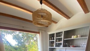 A dining area with a wooden table and chairs, a hanging light fixture, and a kitchen with white cabinets and shelves. - Beautiful Family Villa in Javea, Private pool, Free Wifi, Parking (Xàbia)