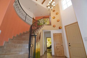 Eine Treppe mit schmiedeeisernem Geländer, einer Holztür und einer Kristallleuchter.