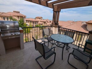 An outdoor patio with a grill, table, and chairs.