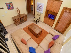 A living room with a sofa, a wooden cabinet, a television, and artwork on the walls.