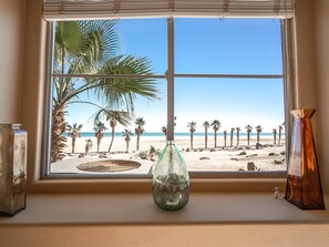 Ein Fenster mit Blick auf einen Strand, Palmen und einen klaren Himmel.