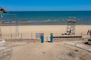 Praia com uma torre salva-vidas, área cercada e placa indicando proibido estacionar.