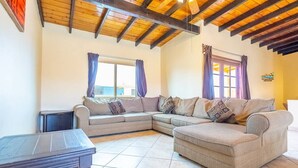 A living room with a sectional sofa, a small table, and a window with curtains.