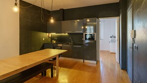 Una cocina moderna con electrodomésticos de acero inoxidable, una mesa de comedor de madera e iluminación colgante.