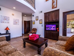 A living room with patterned sofas, a dark wooden coffee table, a television, and artwork on the walls.