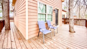 A wooden cabin with a deck, two blue chairs, and a black door. - Luxury Treehouse Eagles Nest (Clarks Hill)