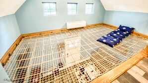 A room with a sloped ceiling, a bed with a mesh cover, and three small windows. - Luxury Treehouse Eagles Nest (Clarks Hill)