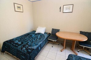Um quarto pequeno com uma cama, uma mesa redonda e duas cadeiras.