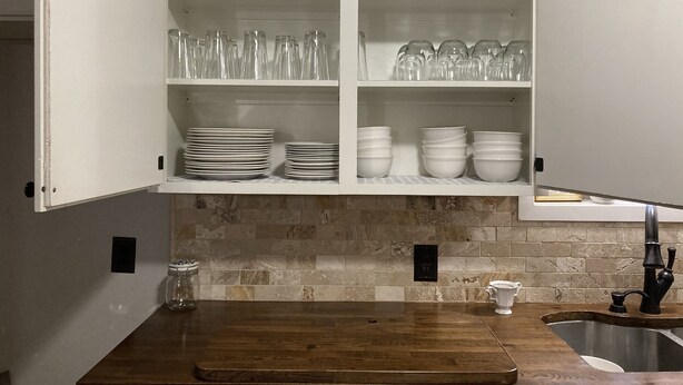 A kitchen with white cabinets, a wooden countertop, and a tiled backsplash. - NEAR BRAZOS COUNTY EXPO CENTER. ENJOY FRESH AIR AND STARRY NIGHTS. (Bryan)
