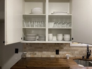 A kitchen with white cabinets, a wooden countertop, and a tiled backsplash. - Steps to Brazos County Expo 2 Acres + Fire Pit  Sleeps 9 (Bryan)