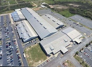 An aerial view of a large industrial building with multiple parking lots and a flat roof. - Steps to Brazos County Expo 2 Acres + Fire Pit  Sleeps 9 (Bryan)
