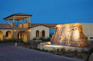 Ein Resort mit Steinaußenwand, einer überdachten Terrasse und einem Wasserfall.