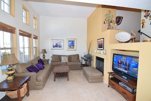 A living room with a sofa, a coffee table, a fireplace, and a television.