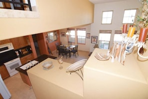 A kitchen with a central island, dining area with chairs, and a view of the outdoors.
