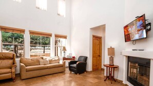 A spacious living room with a beige sofa, a black armchair, and a television mounted on the wall. - Condo 21-1 El Dorado Ranch (San Felipe)