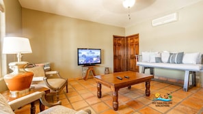 Un salon avec une télévision, un canapé, une table basse et une lampe.